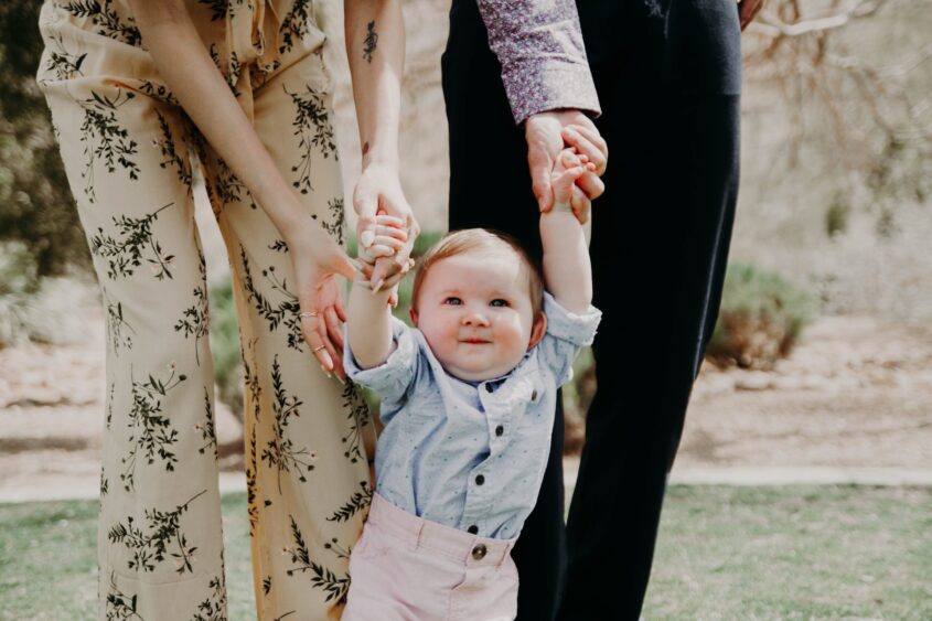 Picture of couple holding hand of toddler walking on grass