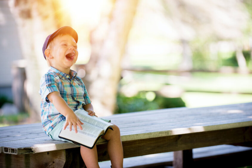Picture of laughing Child sitting on bench with book