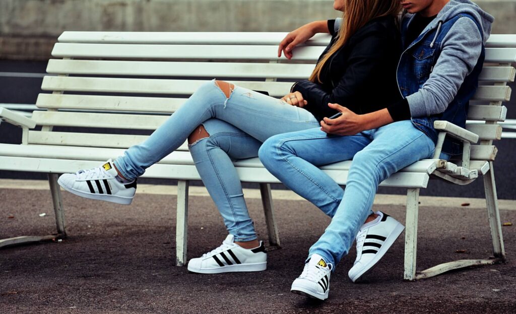 Picture of couple sitting on bench wearing jeans