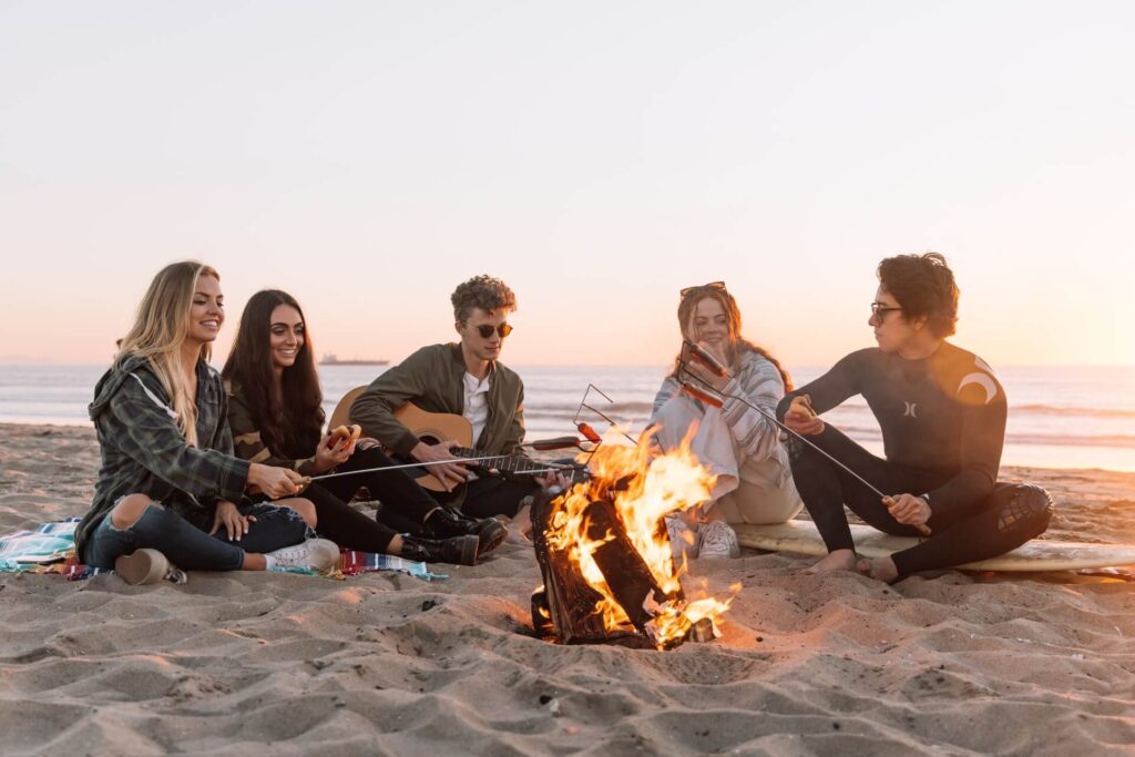Picture of friends sitting across fire playing guitar