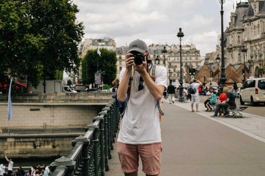 Picture of man holding DSLR camera beside bridge