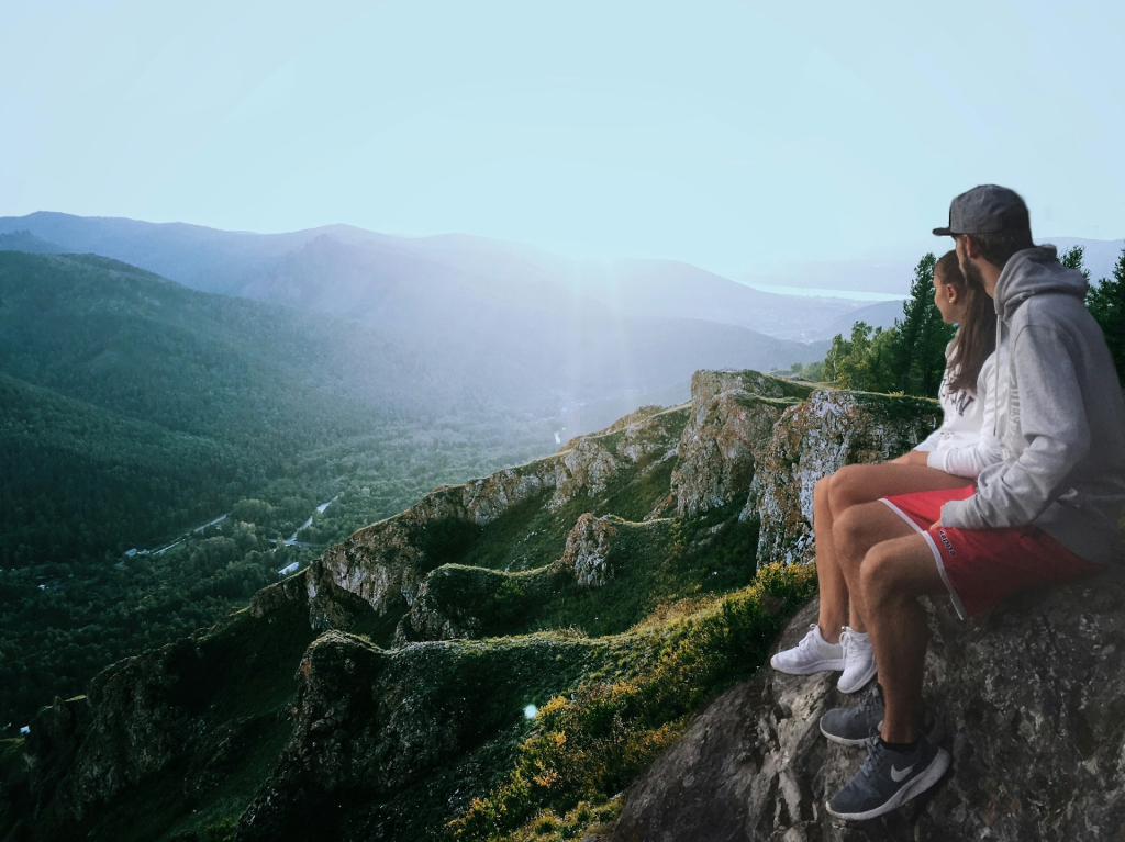 Picture of couple sitting on edge of mountain after hiking